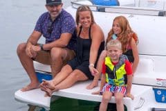 Two parents and two young children enjoying the deck boat features on a Splendor Boats catamaran deck boat.