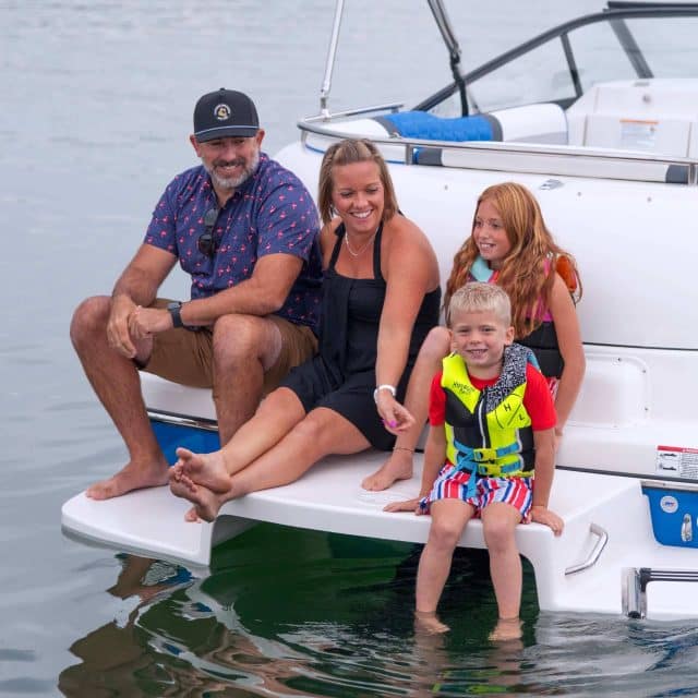Two parents and two young children enjoying the deck boat features on a Splendor Boats catamaran deck boat.