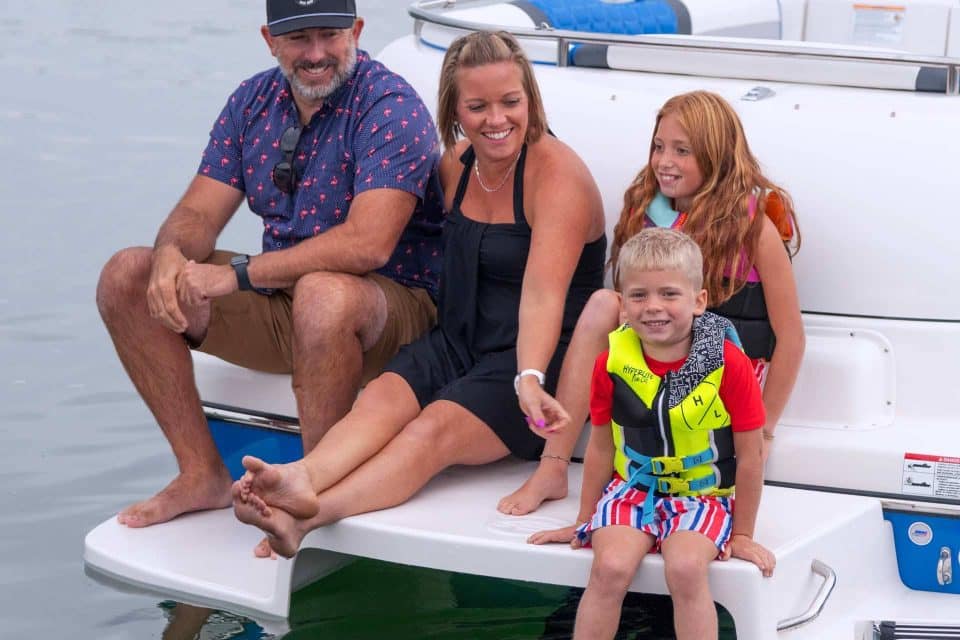 Two parents and two young children enjoying the deck boat features on a Splendor Boats catamaran deck boat.