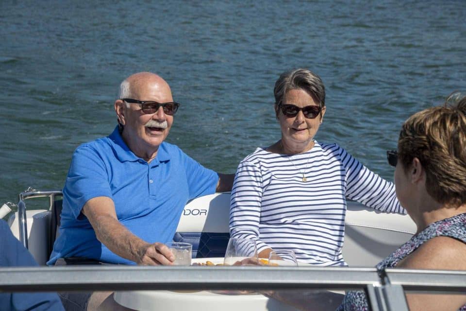 Three older Caucasian adults sitting and talking while in a Splendor deck boat.